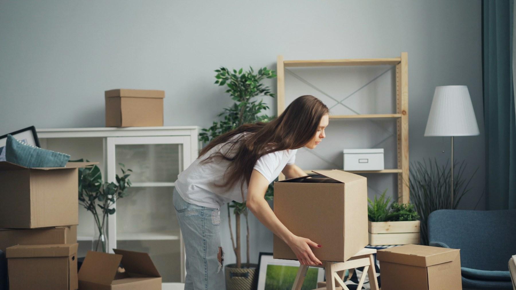 A person carrying a moving box through a home