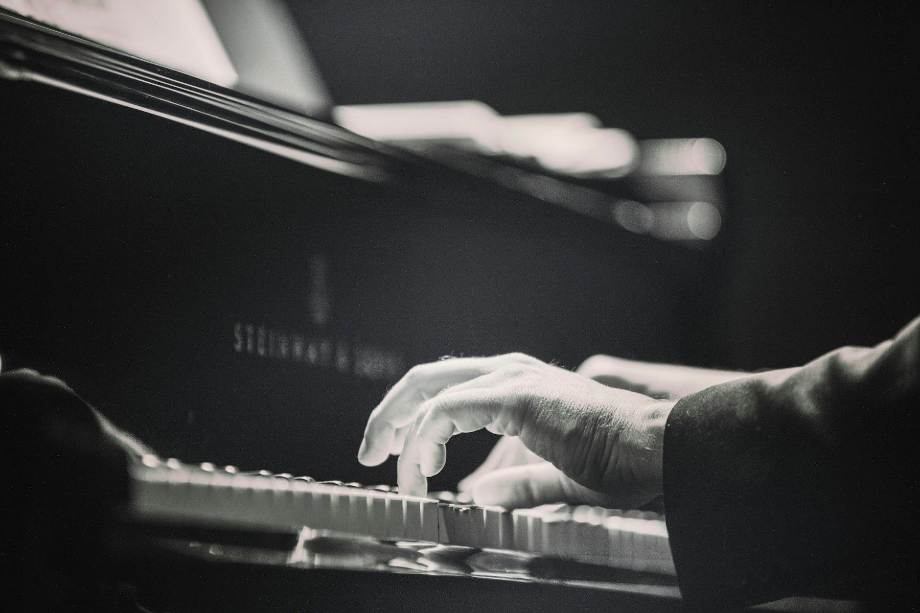 Hands playing a black piano keyboard